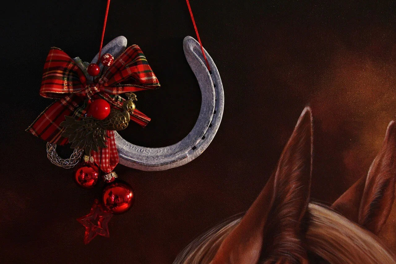 Hufeisen mit roter Schleife und Weihnachtskugeln, Pferdeohren im Hintergrund, Süße Grüße zu Weihnachten – Backe deine eigenen Pferdeleckerlies für die Festtag