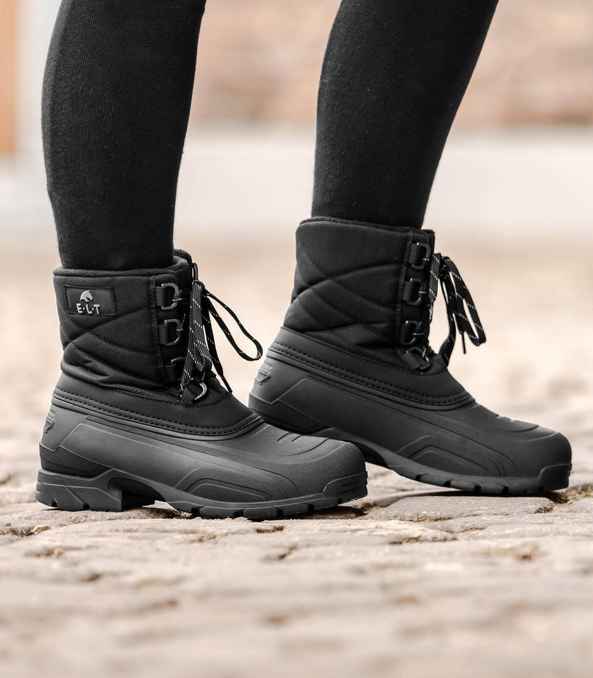 E.L.T Thermoschuh Chicago, Schwarz, an den Füßen einer Person auf Pflaster.