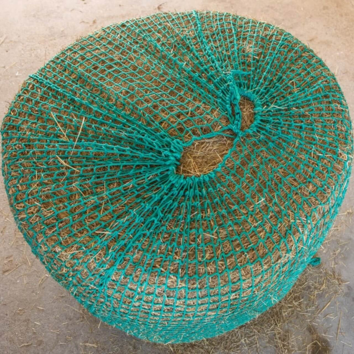 Kerbl Heunetz für Rundballen zum Aufhängen, Türkis, Rundballen mit Heunetz auf dem Boden.