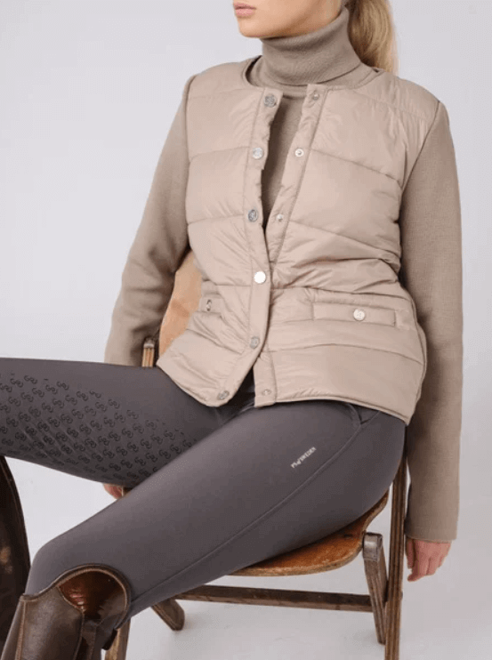 Jacke Damen Perla HW 2021 Steppweste Merinojacke, Beige, Frau sitzt mit der Weste auf einem Stuhl.