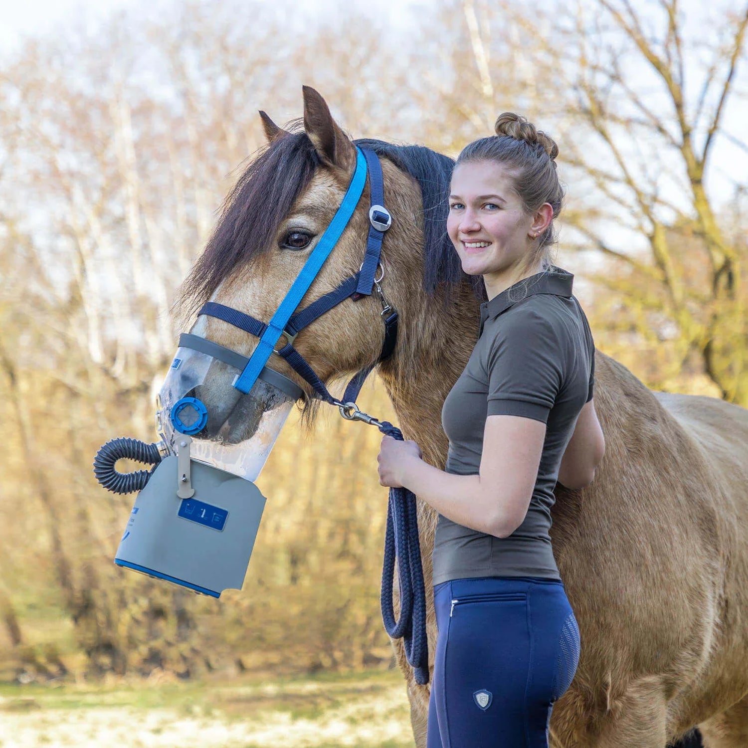 Pferd mit Atemmaske neben Reiterin im Freien, Husten beim Pferd: Ursachen, Behandlung und Tipps zur Vorbeugung