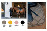 Reiterin steht mit Pferd vor Stall, Schabracke in Smokey Taupe, Golden Yellow, Soft Rouge und Black, Die PLATINUM-KOLLEKTION 2025 by #ESKADRON.