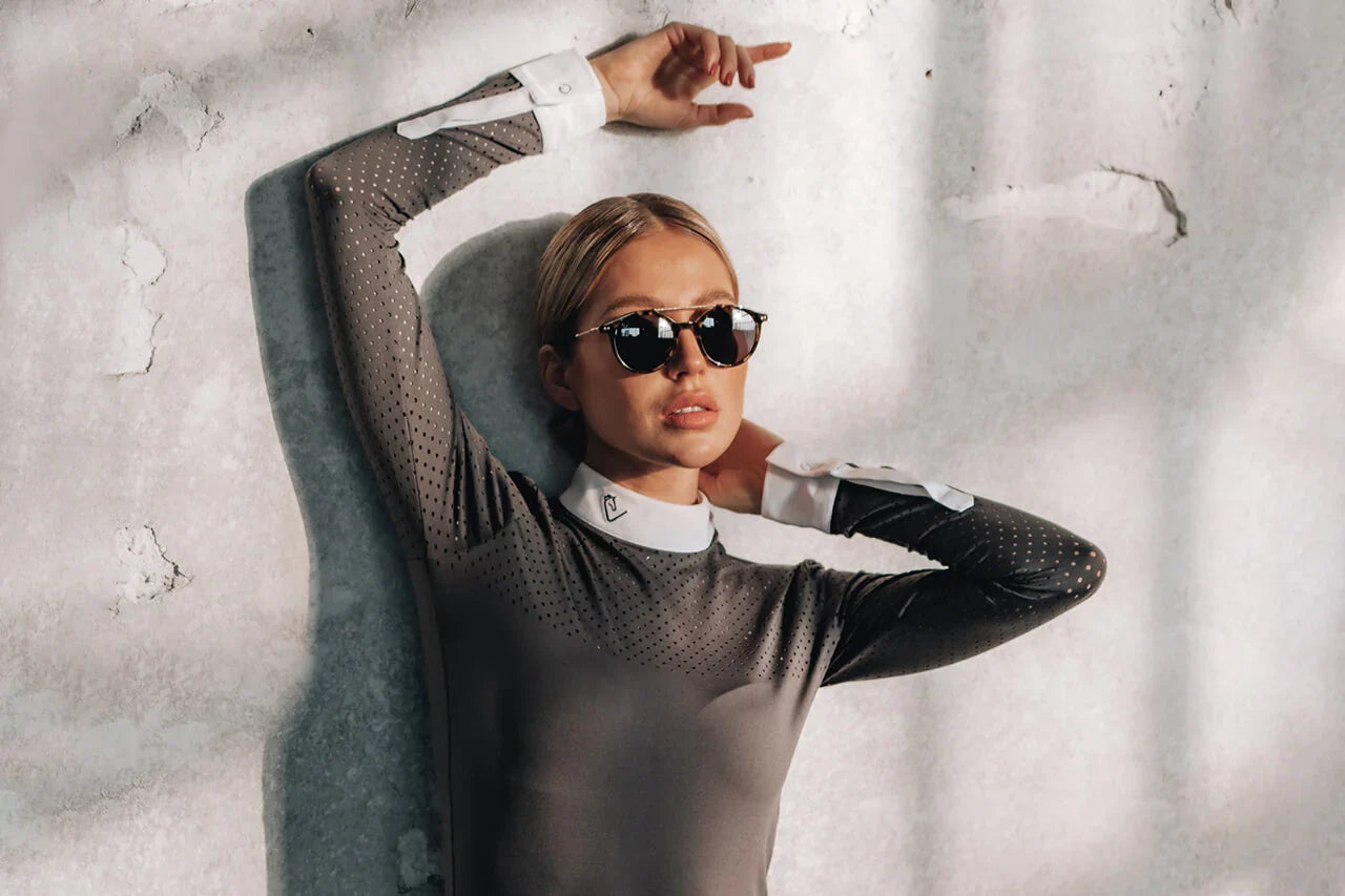 Frau mit Sonnenbrille und Reitoberteil vor heller Wand, Étalon Vert – Was unsere neue Top-Brand zu deinem nachhaltigen Must-Have macht.