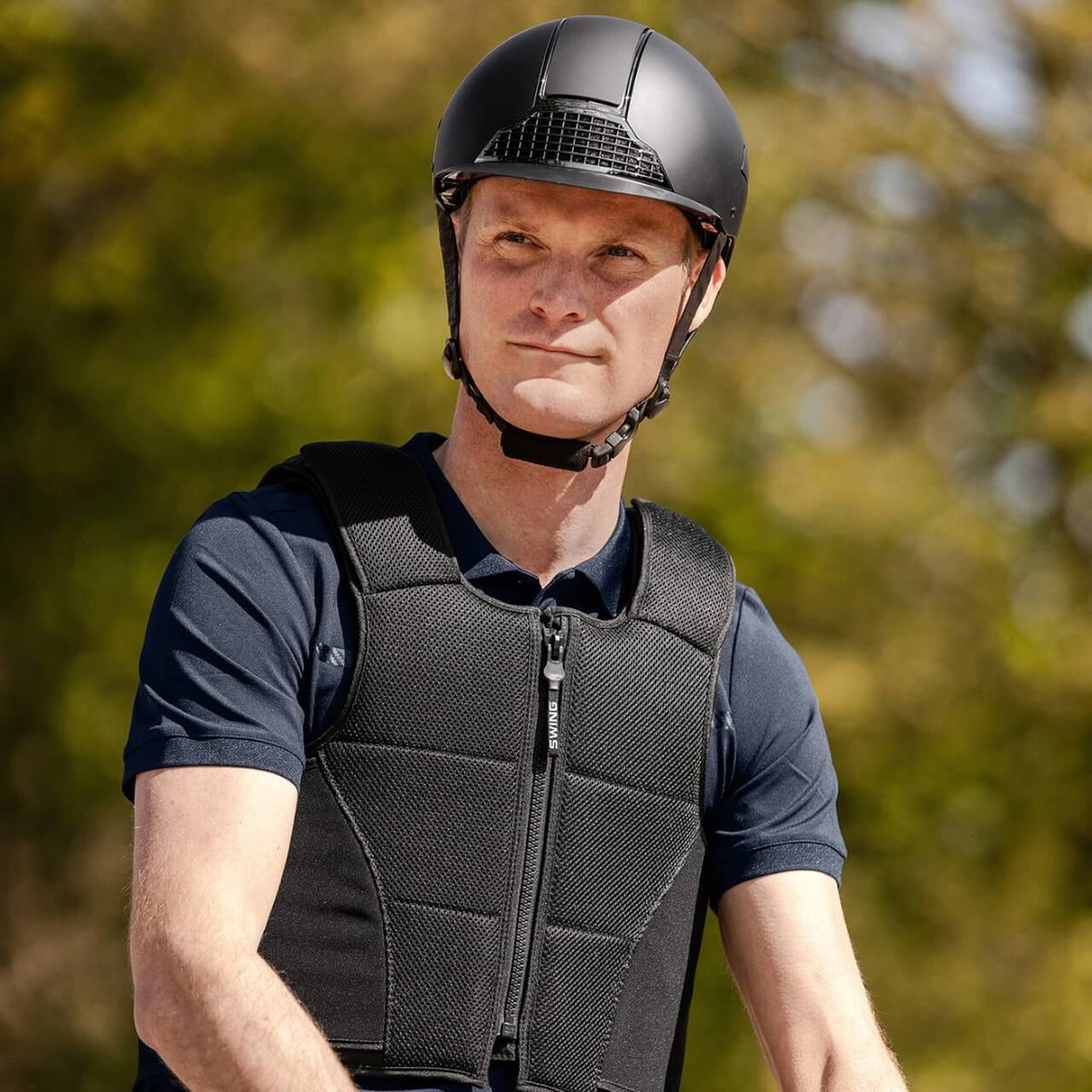 Reithelm Unisex H24 Chrome, Schwarz, Mann trägt den Helm beim Reiten.