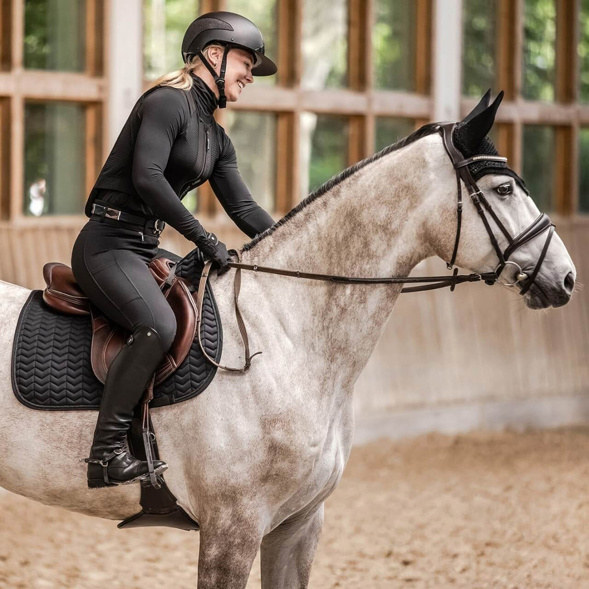 Swing Reithelm Damen H24 Lady Shine, Schwarz, Reiterin auf grauem Pferd in der Reithalle.
