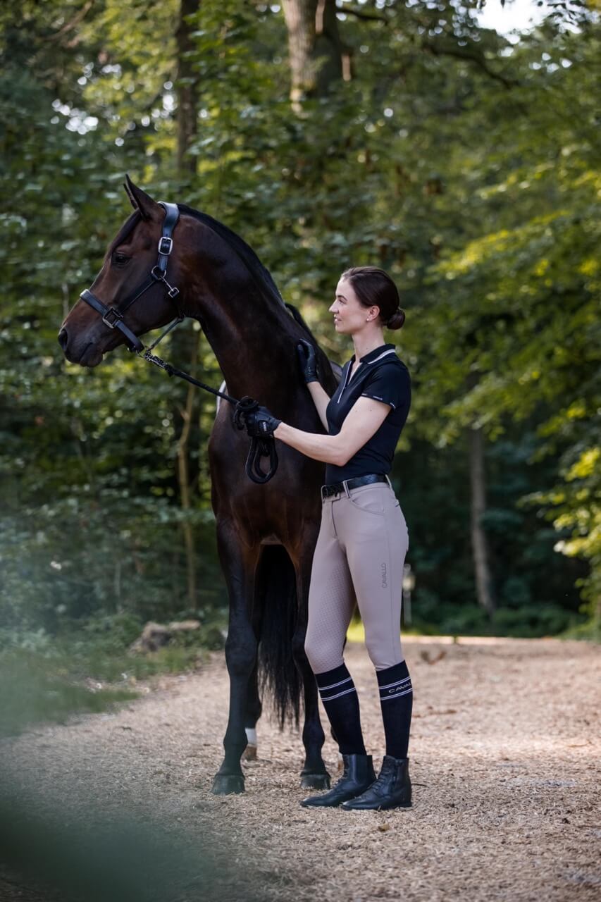 Cavallo Poloshirt CAVALPIQUE Shirt, Schwarz, Reiterin neben Pferd im Freien.