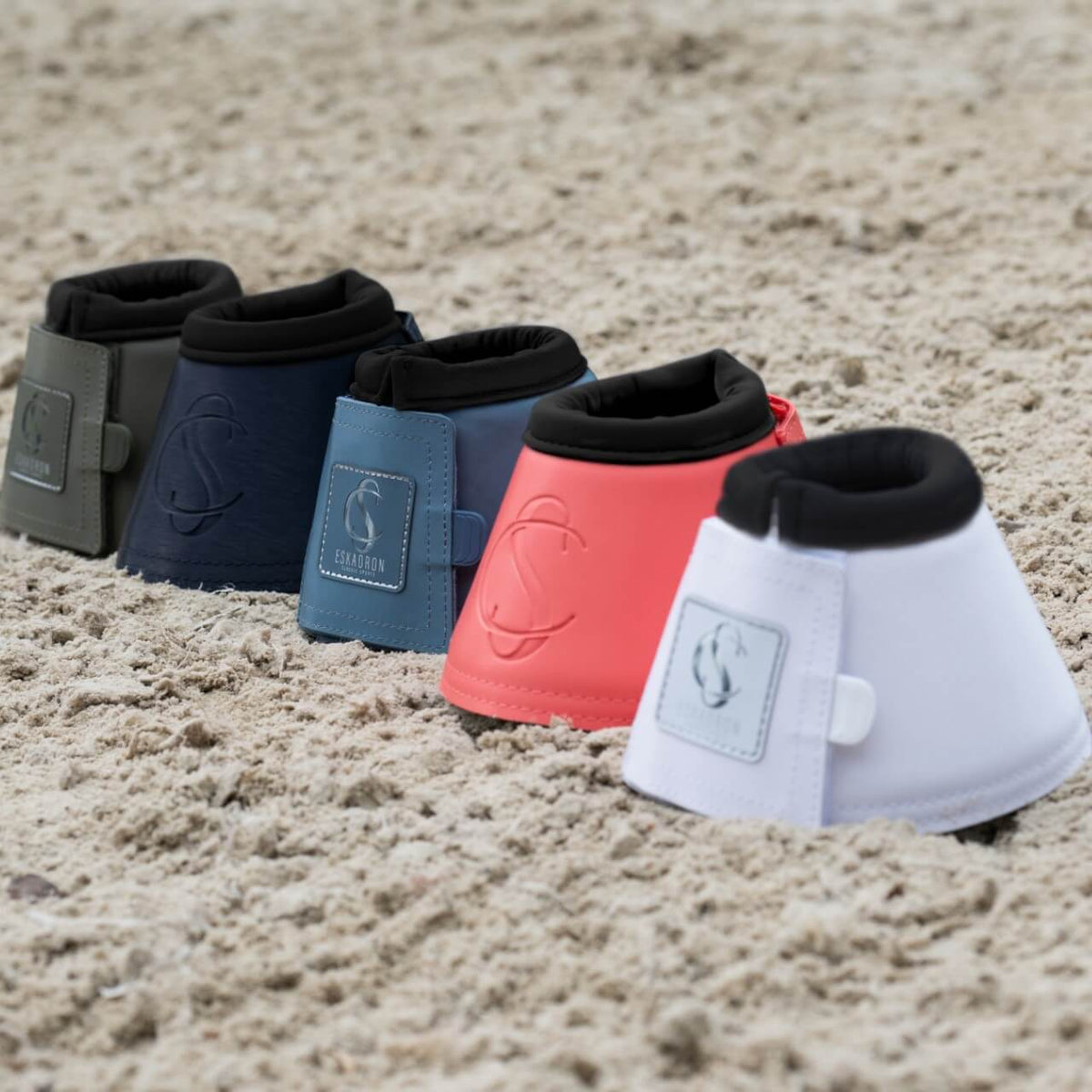 Eskadron Hufglocken Softslate Classic Sports FS25 Sprungglocken, mehrere Farbvarianten, auf Sand ausgelegt.