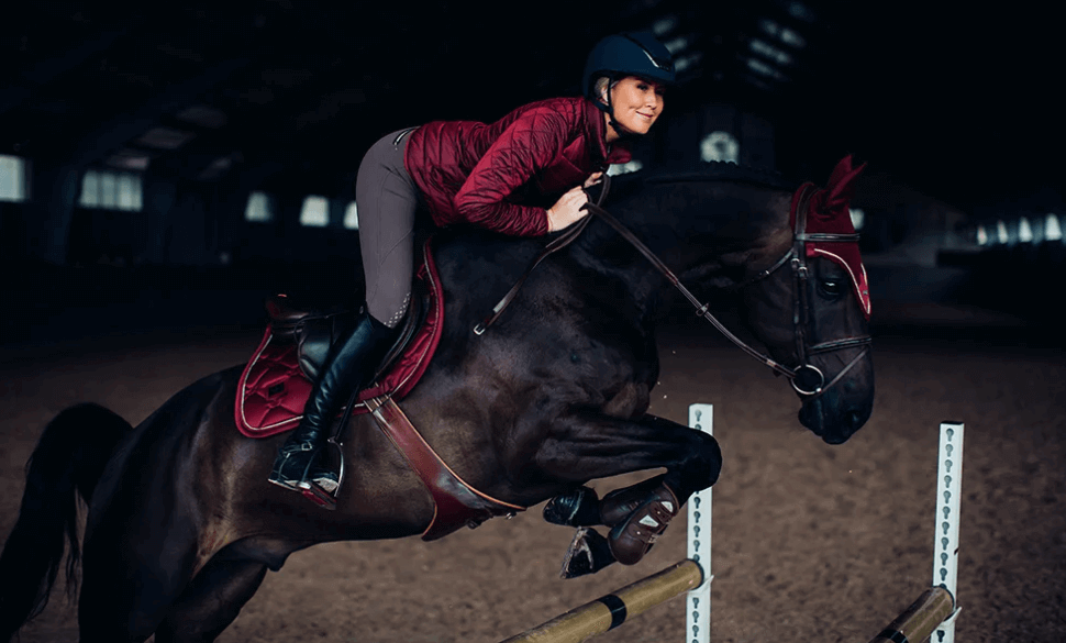 Reithose Jump Elite, Grau, Reiterin auf springendem Pferd in der Reithalle.