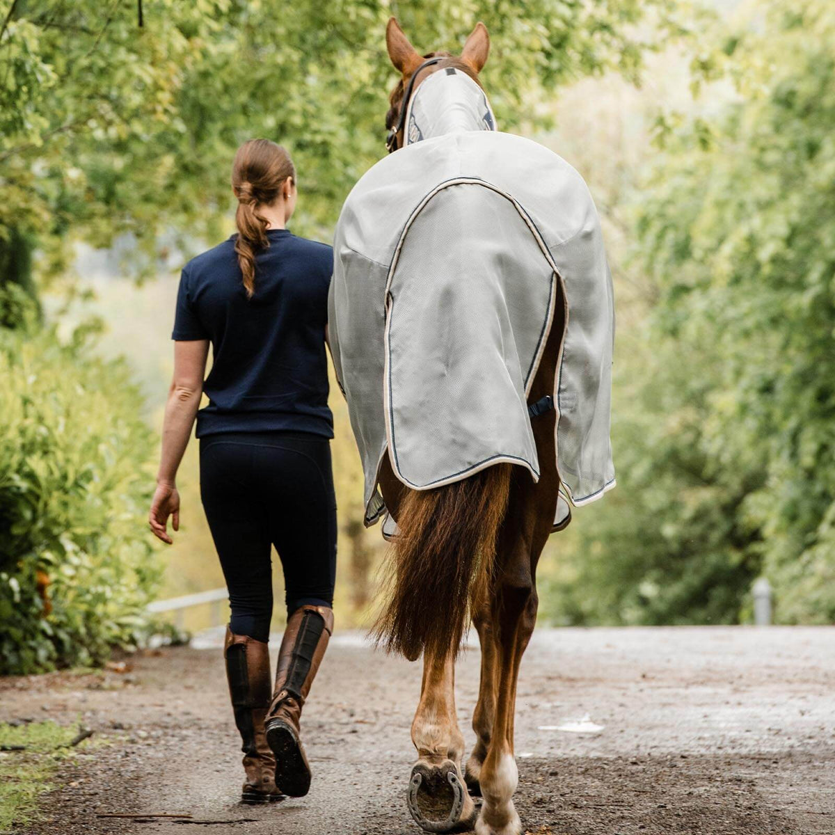 Horseware Ireland Fliegendecke Rambo Protector Plus, Grau, Pferd und Person auf Waldweg.